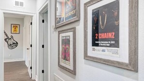 Ein Flur mit gerahmten Postern an der Wand, einer Tür und einer Gitarren-Wanddekoration.