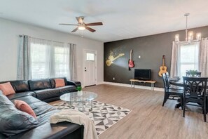 A living room with a sofa, coffee table, and a dining area with chairs and a table. - ♫Rock n’ Roll Bungalow♫Balcony☞3 King Beds ☜ (Tampa)