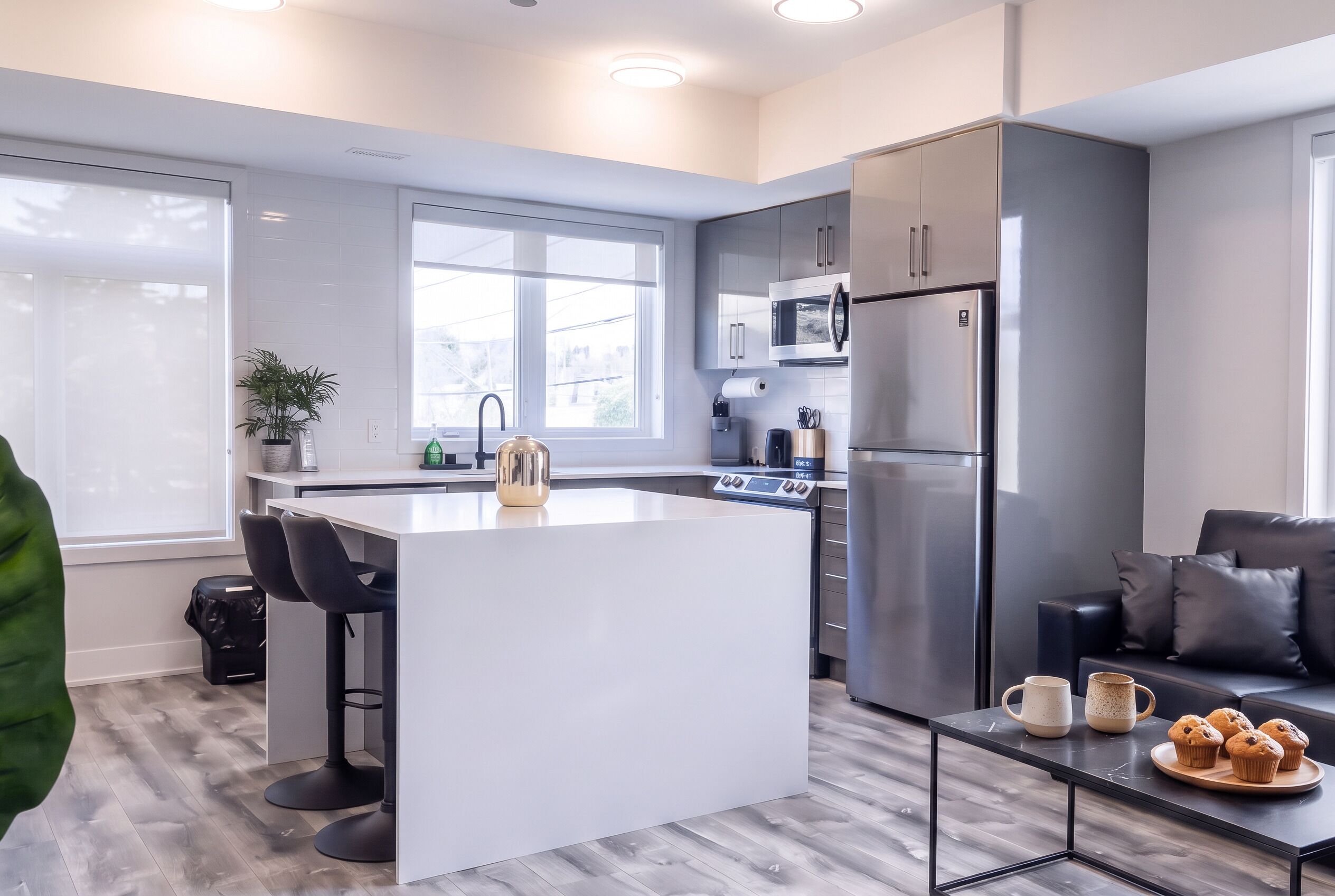 A modern kitchen with a central island, stainless steel appliances, and a seating area with a coffee table.