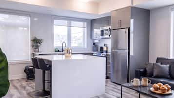 A modern kitchen with a central island, stainless steel appliances, and a seating area with a coffee table.