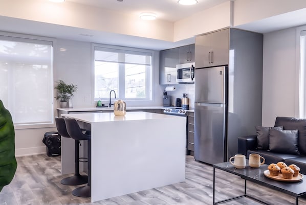 A modern kitchen with a central island, stainless steel appliances, and a seating area with a coffee table.