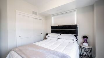 A neatly made bed with white bedding and a headboard with a black panel.