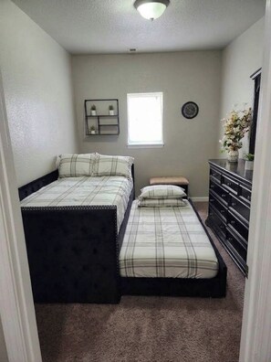 A bedroom with a double bed, a nightstand, a dresser, a window, and a wall-mounted shelf. - Beautiful 2-bedroom house with AC & WIFI in Colorado Springs, close to downtown (Colorado Springs)