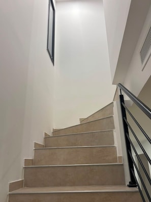 A staircase with beige steps and a black handrail, leading upwards in a modern interior. - Modern Villa with Private Pool in Vias – Your Perfect South of France Getaway ☀️ (Vias)