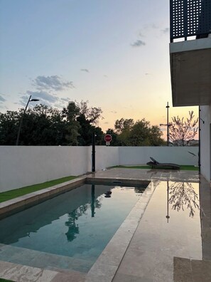 A swimming pool with a stop sign in the background, surrounded by a white wall and greenery. - Modern Villa with Private Pool in Vias – Your Perfect South of France Getaway ☀️ (Vias)