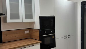Eine moderne Küche mit weißen Schränken, einem schwarzen Backofen und einer Holzarbeitsplatte.