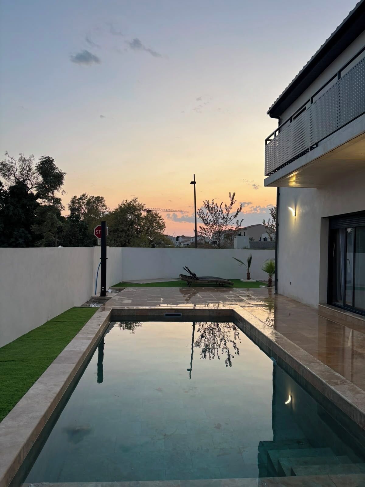 Une piscine rectangulaire offrant une vue dégagée sur le ciel et sur un chantier de construction situé au loin.
