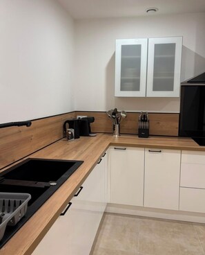 Een moderne keuken met een zwart fornuis, witte kastjes en een houten aanrecht.