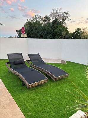 Two lounge chairs on artificial grass with a stop sign and trees in the background. - Modern Villa with Private Pool in Vias – Your Perfect South of France Getaway ☀️ (Vias)