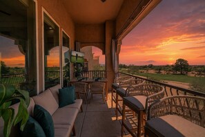 A balcony with outdoor furniture, a television, and a view of a sunset over a golf course. - TPC Golf Condo/Patio/Golf Course View/Sleeps 8/Community Pool/Hot Tub (Scottsdale)