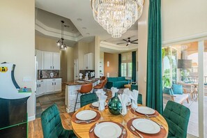 A dining area with a wooden table set for four, a chandelier, and a view of the kitchen and living area. - TPC Golf Condo/Patio/Golf Course View/Sleeps 8/Community Pool/Hot Tub (Scottsdale)