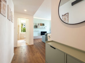 A hallway leading to a bathroom with a wooden floor, a kitchen area with a TV, and a dining area with a table and chairs. - Genzianella Alpine Apartment by Interhome (Chiavenna)