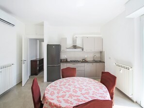 A compact kitchen with a dining table, chairs, and a refrigerator. - Attico Alda by Interhome (Rapallo)