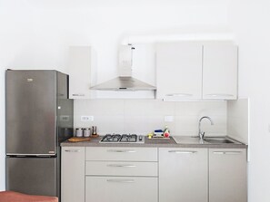 A modern kitchen with stainless steel appliances, white cabinetry, and a built-in oven. - Attico Alda by Interhome (Rapallo)