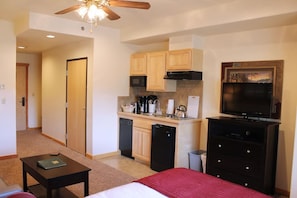 A compact hotel room with a kitchenette, a bed, a television, and a ceiling fan. - Delightful studio in Breckenridge winter wonderland -mountain/ski getaway (Breckenridge)