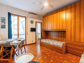 A compact room with a wooden bunk bed, a dining table with chairs, a small table, and a ceiling fan. - Margherita by Interhome (Santo Stefano al Mare)