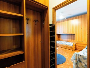 Une pièce avec une armoire en bois, un lit recouvert d’une courtepointe à motifs bleus et blancs, et un petit tapis rond.