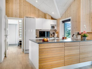 Una cocina moderna con paneles de madera, armarios blancos y una isla central.