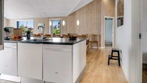 A modern kitchen with a central island, wooden panel walls, and a dining area with a view. - "Arsi" - 350m from the sea by Interhome (Thisted)