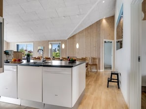 A modern kitchen with a central island, wooden panel walls, and a dining area with a view. - "Arsi" - 350m from the sea by Interhome (Thisted)