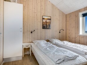 A bedroom with two beds, a wardrobe, a bedside table, and a window. - "Arsi" - 350m from the sea by Interhome (Thisted)
