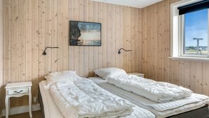 A room with two beds, a small bedside table, a wall-mounted picture, and a window with a view. - "Arsi" - 350m from the sea by Interhome (Thisted)