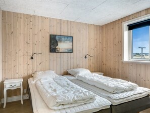 A room with two beds, a small bedside table, a wall-mounted picture, and a window with a view. - "Arsi" - 350m from the sea by Interhome (Thisted)