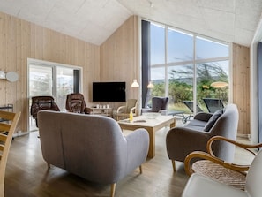 A modern living room with a large TV, comfortable seating, and a view of the outdoors. - "Arsi" - 350m from the sea by Interhome (Thisted)