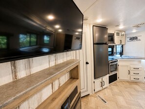 A modern kitchen with a built-in oven, microwave, and stainless steel refrigerator. - 2-bedroom recreational vehicle in beautiful Shingleton with AC (Shingleton)