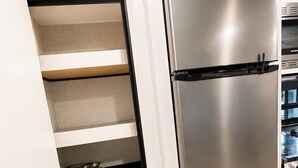 A modern kitchen with a stainless steel Furrion refrigerator, white cabinetry, and a herringbone-patterned floor. - 2-bedroom recreational vehicle in beautiful Shingleton with AC (Shingleton)