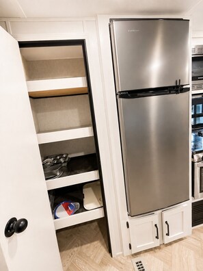 Eine moderne Küche mit einem Edelstahl-Kühlschrank von Furrion, weißen Schränken und einem Fischgrätparkettboden.