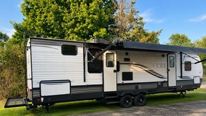 A motorhome with a sliding door, a small window, and a kitchenette area. - 2-bedroom recreational vehicle in beautiful Shingleton with AC (Shingleton)