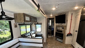 A modern RV interior with a dining area, seating, a kitchen, and a bathroom. - 2-bedroom recreational vehicle in beautiful Shingleton with AC (Shingleton)