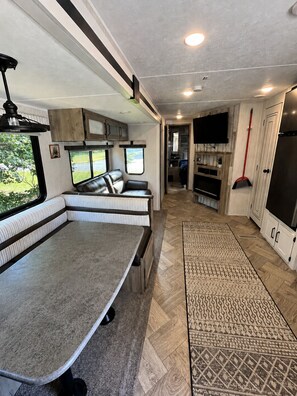 Ein modernes Wohnmobil-Interieur mit Essbereich, Sitzgelegenheiten, einer Küche und einem Badezimmer.