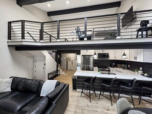 A modern loft apartment with a kitchen, dining area, and a living room with a black leather sofa. - Family-Friendly 3BR Vail Condo near Gore Creek, Steps to Free Bus, 2 Parking Spaces (Vail)