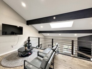 Ein modernes Wohnzimmer mit einer Couch, einem Couchtisch und einem an der Wand befestigten Flachbildfernseher.