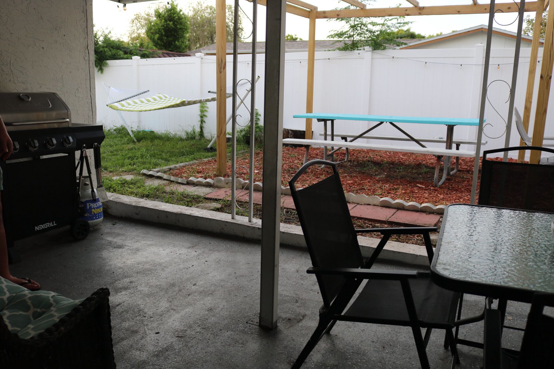 A patio area with a grill, a table, and chairs.