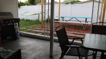 A patio area with a grill, a table, and chairs.