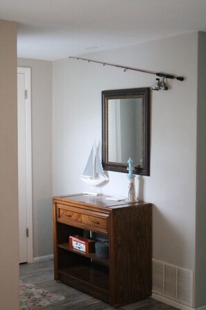 A room with a wooden dresser, a mirror, a small sailboat model, and a fishing rod.