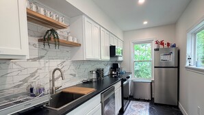 A modern kitchen with white cabinets, a black countertop, and a stainless steel refrigerator.