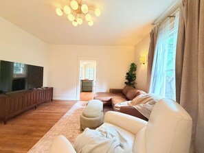 Ein Wohnzimmer mit Flachbildfernseher, einer Couch, einem Couchtisch und einer Pflanze.