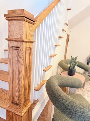 Eine Holztreppe mit weißen Geländern und einem grünen Sitz mit einem Blumentopf.