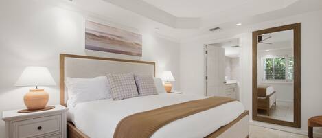 A bedroom with a bed, bedside tables, a ceiling fan, a painting, and a mirror.