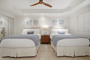 Ein Schlafzimmer mit zwei Betten, einem Deckenventilator und Bildern an den Wänden.