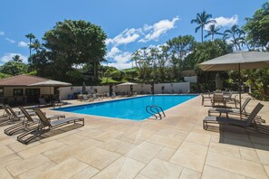 A swimming pool with lounge chairs and umbrellas, surrounded by palm trees and a clear sky. - Newly Remodeled/Refurnished Oceanfront Makena Surf Condo - Ground Floor (Kihei)