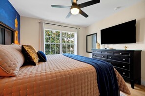 Ein Schlafzimmer mit Bett, Deckenventilator, Fenster und Fernseher.