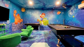 A pool table with a Mario character, green chairs, and a space-themed wall mural. - Windsor Hills 5BR/5BA | Pool & Spa, Game Room, 2 Miles to Disney, Themed (Kissimmee)