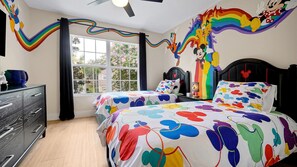 Un dormitori amb dos llits, un aparador, una finestra amb cortines i un mural a la paret.