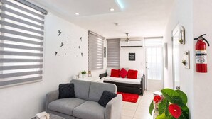 A modern living room with a grey sofa, a red and white bed, and a ceiling fan. - Private Jacuzzi • Rooftop Escape • Ponce (Ponce)