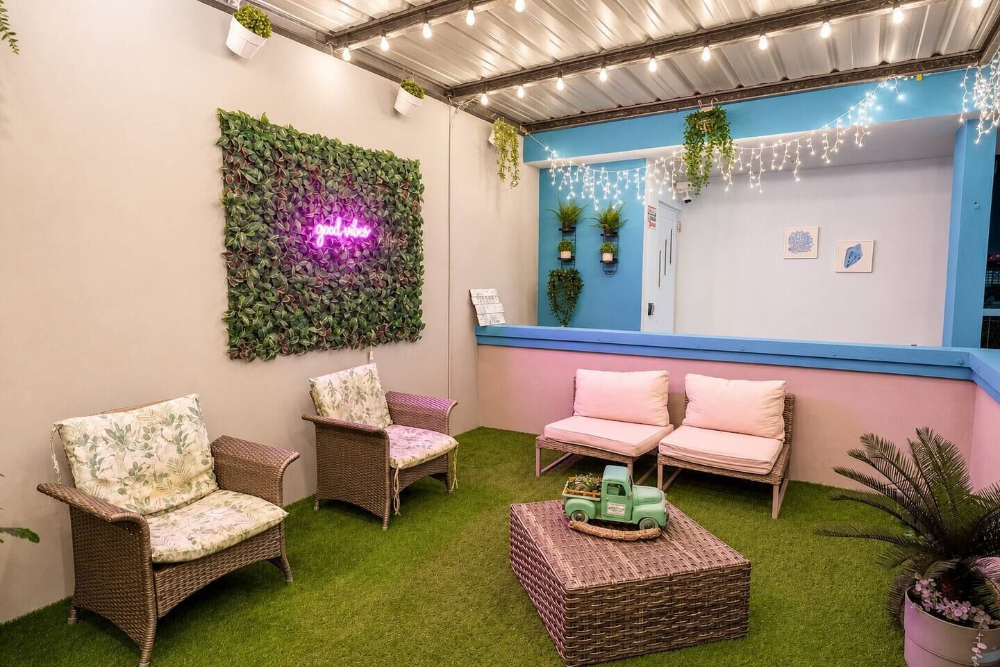 A cozy outdoor seating area with wicker furniture and a neon sign.